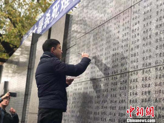 10日晨，下著小雨。南京大屠殺幸存者、死難者遺屬、學(xué)生們依次描寫名字，祭悼南京大屠殺遇難同胞。淡淡的墨汁摻著雨水，滲入了刻在紀念館灰色厚重石壁上的黑色名字中。　朱曉穎 攝