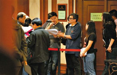 12日，北京麗都飯店，馬航工作人員叫乘客家屬進屋領(lǐng)取慰問金。目前，馬航兩次向乘客家屬發(fā)放慰問金，但未啟動賠償。新京報記者