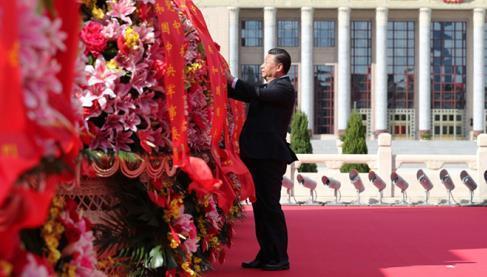 9月30日上午，習(xí)近平等黨和國家領(lǐng)導(dǎo)人來到北京天安門廣場，出席烈士紀(jì)念日向人民英雄敬獻花籃儀式。這是習(xí)近平整理花籃上的緞帶。圖片來源：新華社